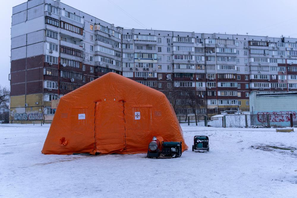 Ein orangenes Zelt vor Häusern im Schnee